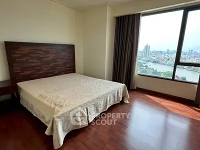 Spacious bedroom with stunning city and river view, featuring elegant wooden flooring and large window.