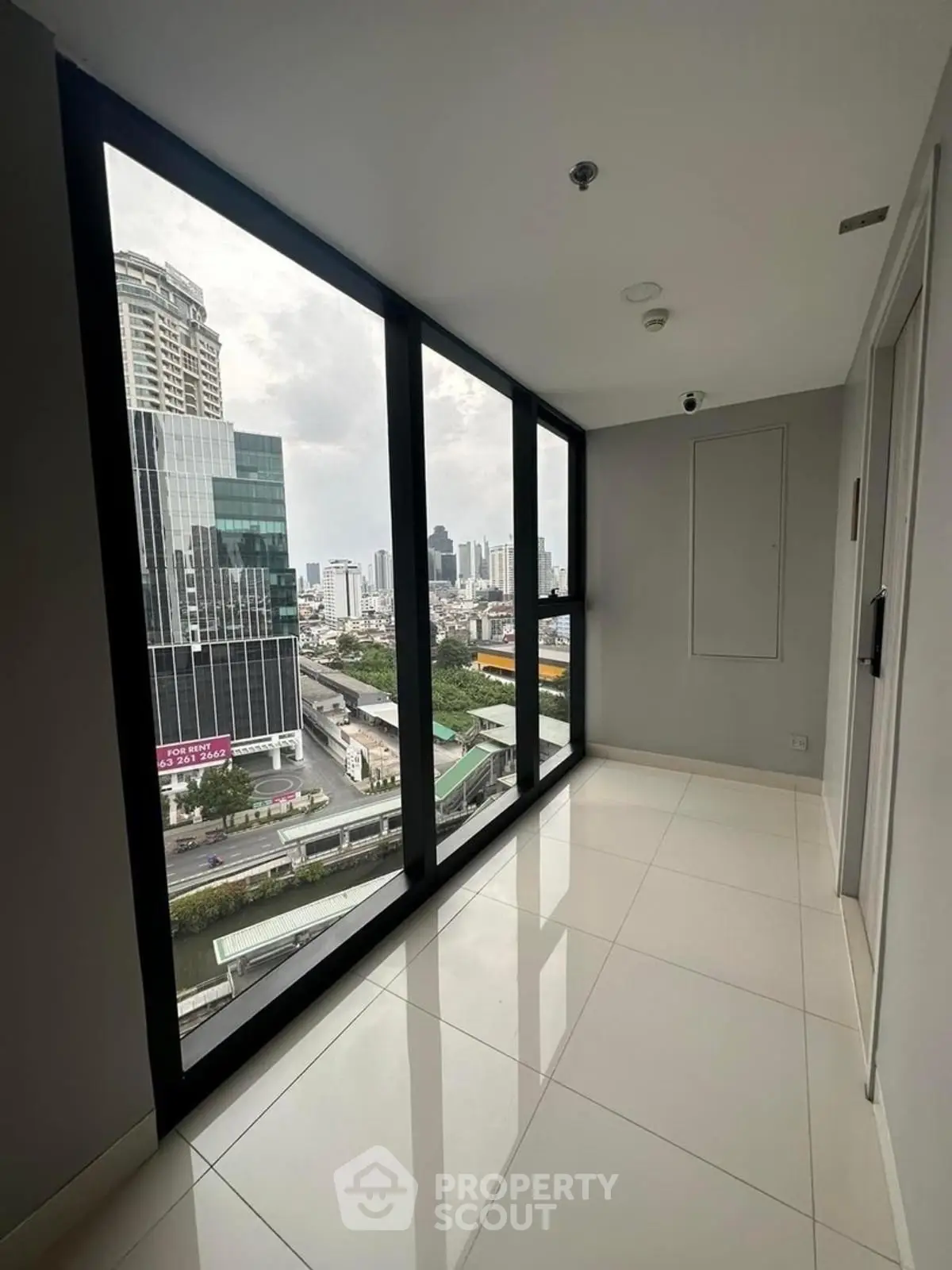 Modern high-rise apartment with stunning city view through floor-to-ceiling windows.