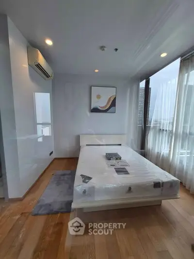 Modern bedroom with large windows and stylish decor in a high-rise apartment.