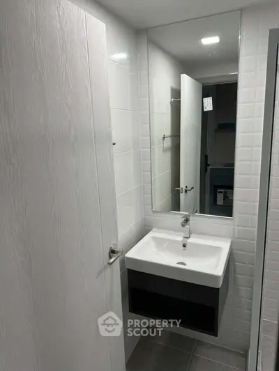 Modern bathroom with sleek sink and large mirror in contemporary apartment.
