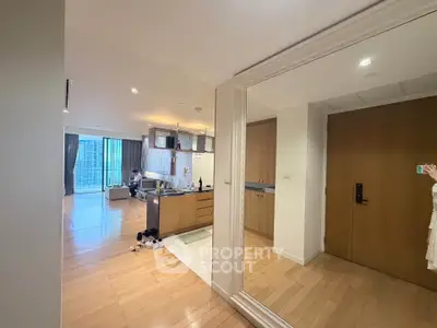 Spacious modern apartment with open kitchen and living area, featuring wooden flooring and large windows.