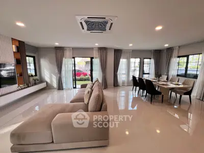 Spacious modern living room with elegant dining area and large windows for natural light.