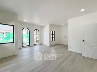 Spacious and bright living room with elegant arched windows and modern flooring.