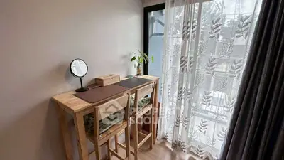 Cozy study nook with wooden desk and chairs by a window with sheer curtains.