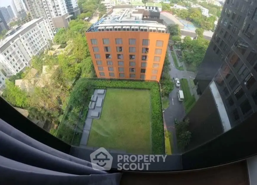 Stunning aerial view of modern apartment complex with lush green courtyard and cityscape backdrop.