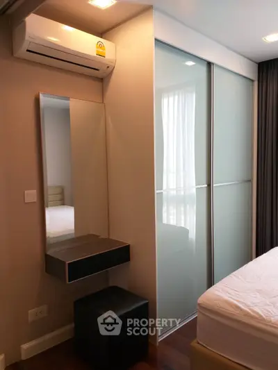 Modern bedroom with sleek design, featuring built-in wardrobe and air conditioning unit.