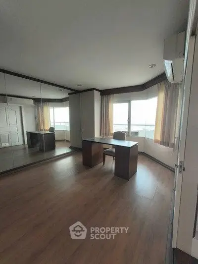 Spacious study room with large windows and wooden flooring, perfect for a home office setup.