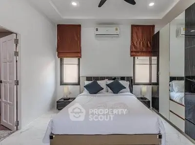 Modern bedroom with stylish decor and air conditioning, featuring a comfortable bed and ample natural light.