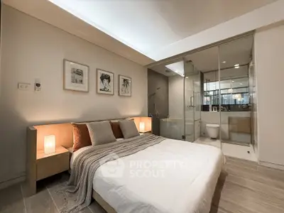 Modern bedroom with ensuite bathroom featuring glass partition and elegant decor.