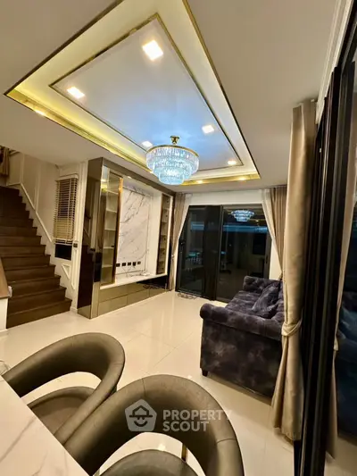 Luxurious living room with elegant chandelier and modern staircase design.