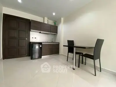 Modern kitchen with sleek cabinets and dining area in a compact apartment.