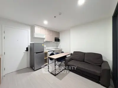 Modern compact living room with integrated kitchen, featuring sleek appliances and cozy seating area.