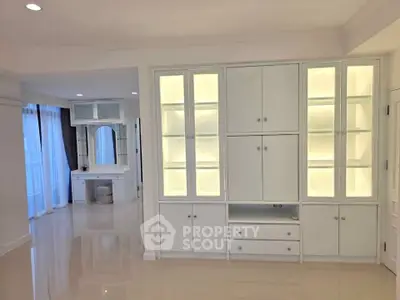 Spacious modern living room with built-in illuminated cabinets and glossy flooring.
