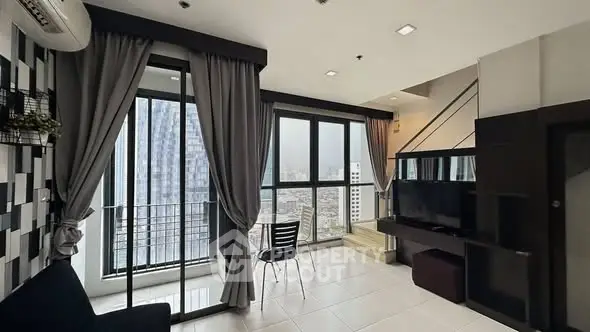 Modern living room with large windows and city view in high-rise apartment.