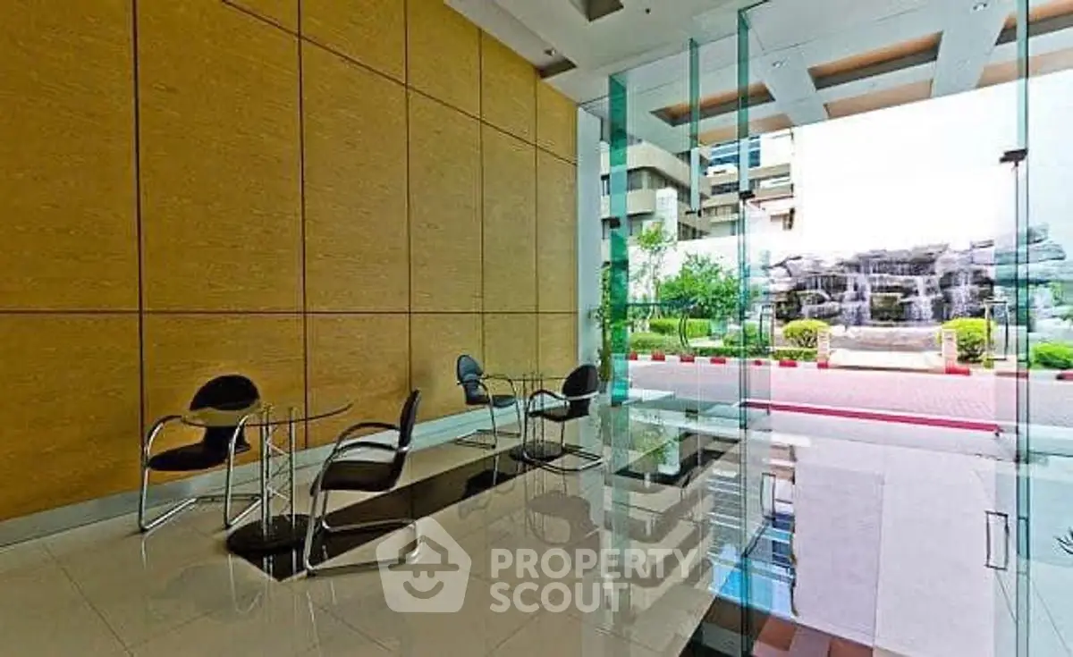 Modern building entrance with glass walls and sleek seating area.