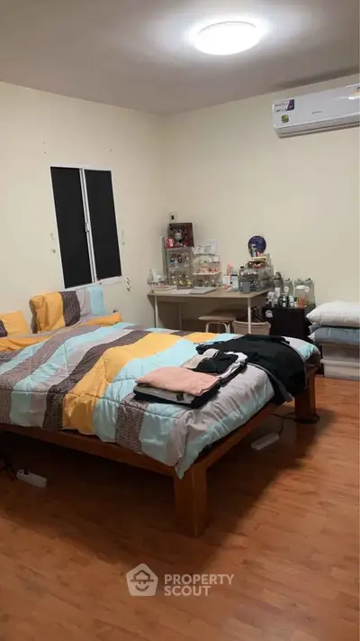 Cozy bedroom with wooden flooring and modern air conditioning unit, perfect for comfortable living.