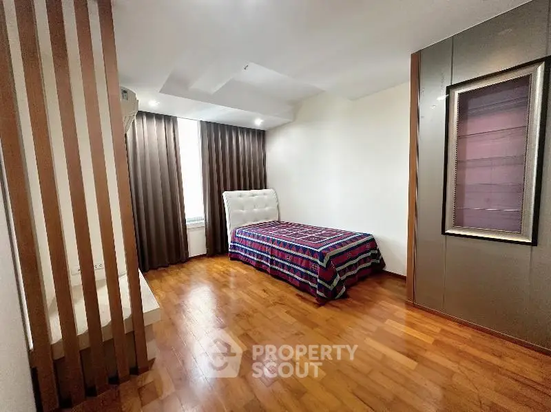 Spacious bedroom with wooden flooring and modern decor in a stylish apartment.