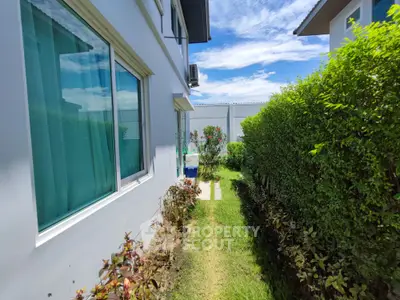 Charming garden path beside modern house with lush greenery and blue sky