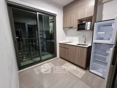 Modern kitchen with open layout and balcony view, featuring sleek cabinetry and appliances.