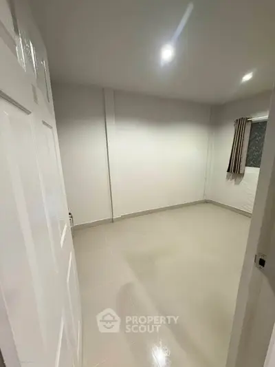 Spacious empty room with tiled floor and window, ideal for customization.