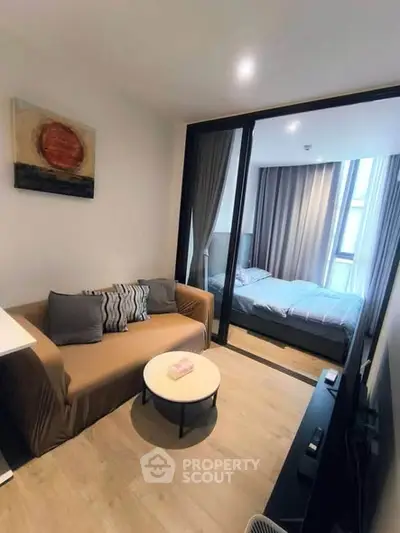 Modern studio apartment with cozy living area and bedroom separated by glass partition.