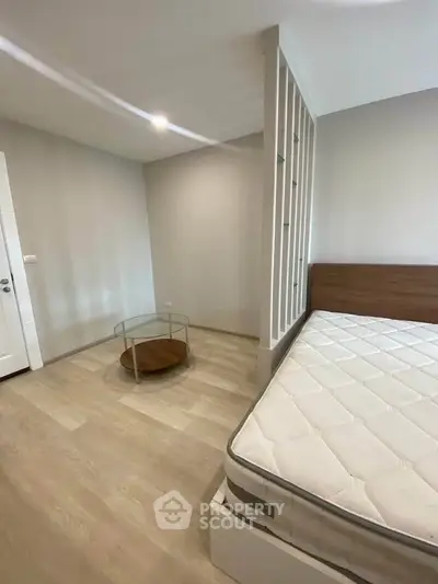 Spacious bedroom with modern design and natural light, featuring a comfortable mattress and stylish decor.