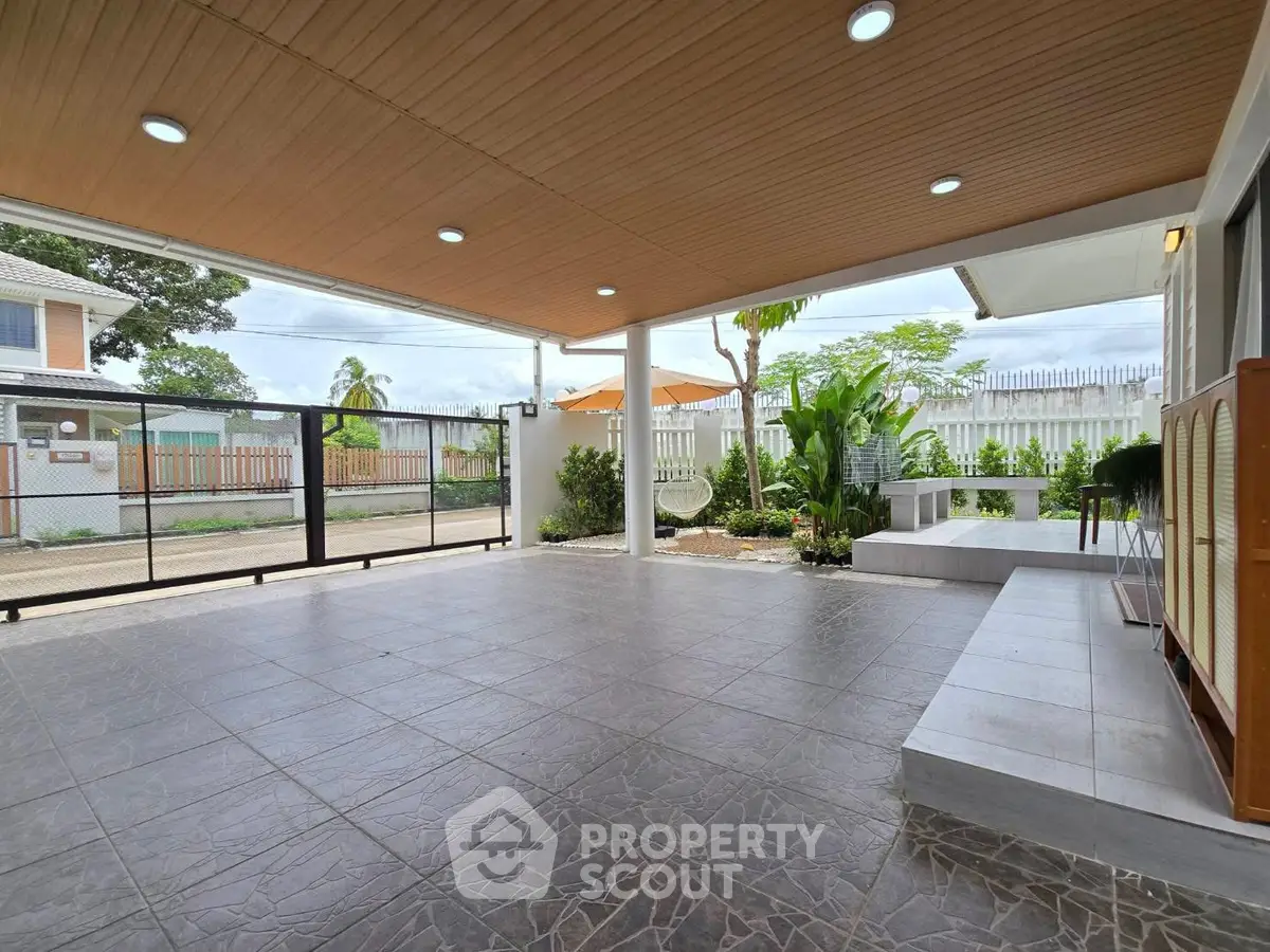 Spacious covered patio with modern tile flooring and garden view.
