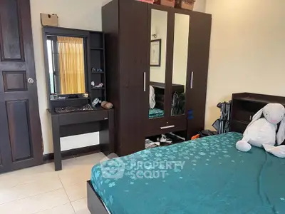 Cozy bedroom with dark wood furniture and teal bedding, featuring a plush toy on the bed.