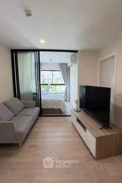 Modern living room with sleek TV unit and cozy sofa, leading to a bright bedroom with balcony view.