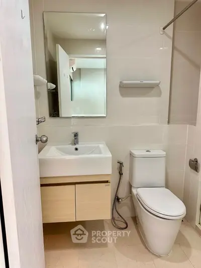 Modern bathroom with sleek fixtures and neutral tones, featuring a stylish sink and toilet.