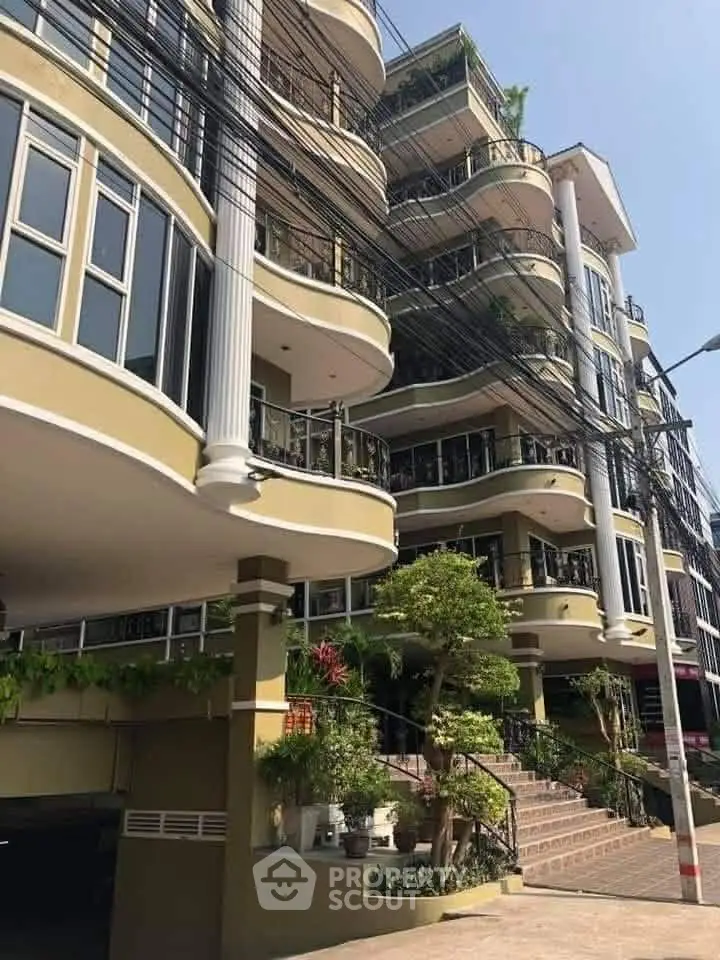 Elegant multi-story building with curved balconies and lush greenery.