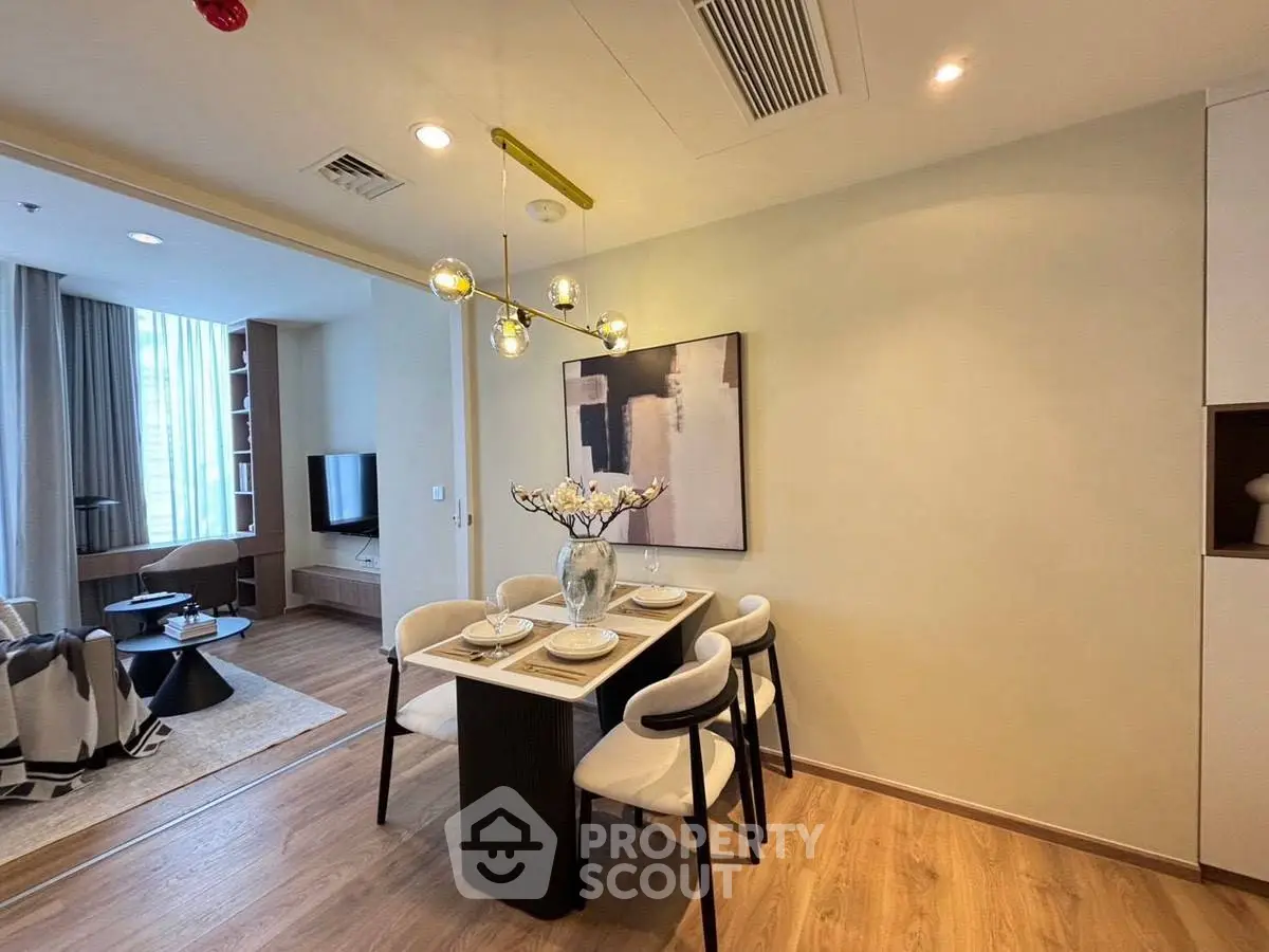 Modern dining area with elegant lighting and open layout to living room