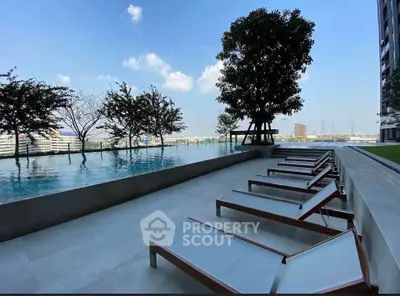 Luxurious rooftop pool with sun loungers and stunning city view, perfect for relaxation and leisure.