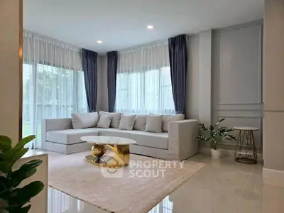 Elegant living room with modern sofa, chic coffee table, and large windows with sheer curtains.