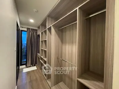 Spacious walk-in closet with wooden shelves and hanging space, perfect for organized storage.