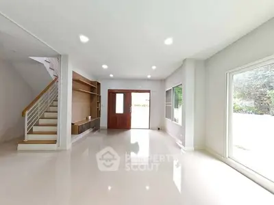 Spacious modern living room with large windows and sleek staircase