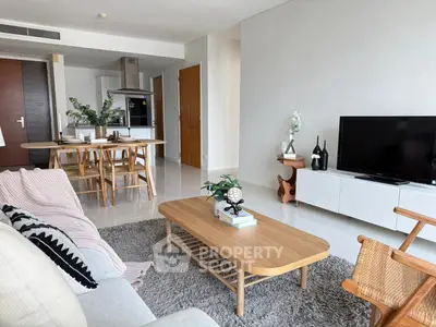 Modern living room with open kitchen, stylish furniture, and cozy decor