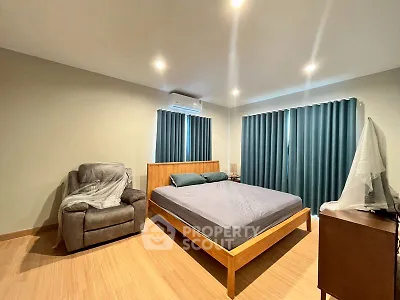 Spacious modern bedroom with cozy armchair and elegant wooden furniture.