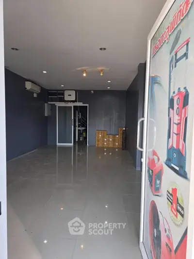 Spacious commercial space with sleek tiled flooring and modern lighting, ideal for retail or office setup.