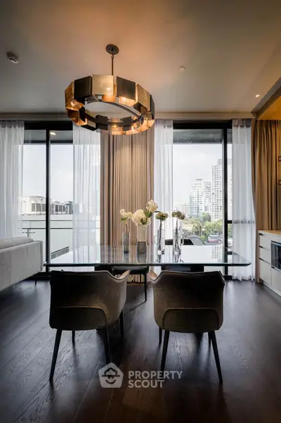 Luxurious dining area with modern chandelier and city view, featuring elegant decor and floor-to-ceiling windows.