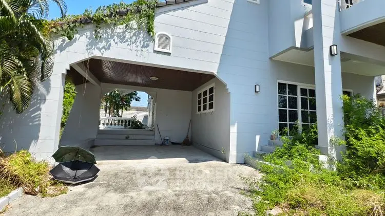 Charming house exterior with covered carport and lush greenery