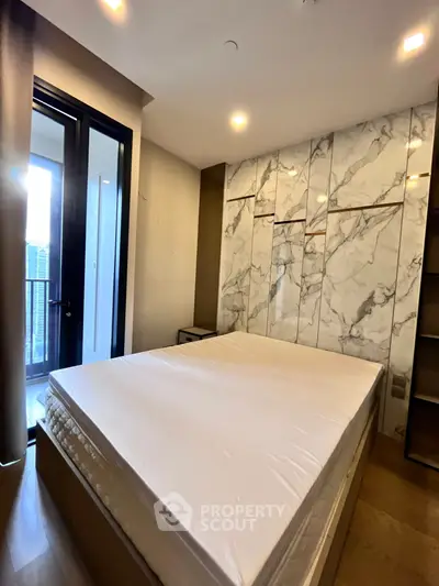 Luxurious bedroom with marble accent wall and balcony access in modern apartment