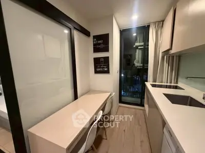 Modern kitchen with sleek design, featuring a dining area and large window for natural light.
