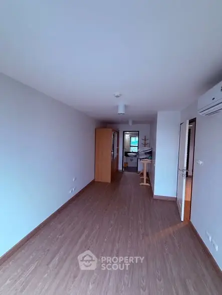 Spacious empty room with wooden flooring and natural light, ideal for customization.