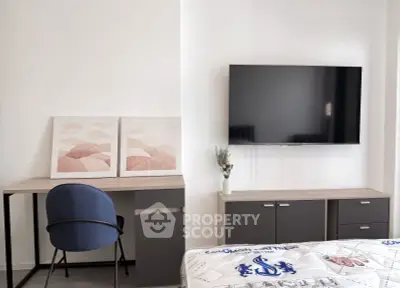 Modern bedroom with wall-mounted TV, stylish desk, and cozy decor
