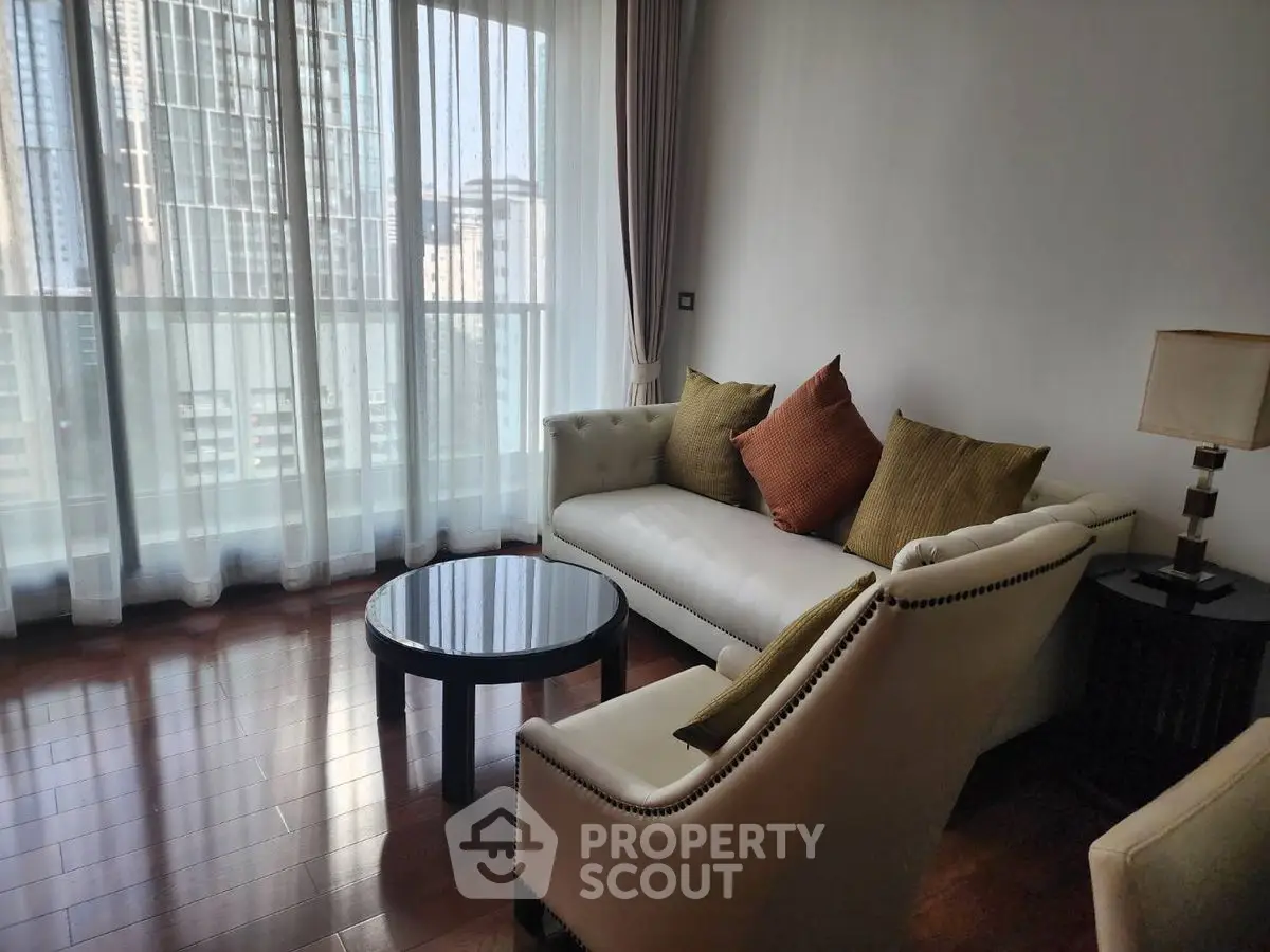 Elegant living room with modern furniture and city view through large windows.