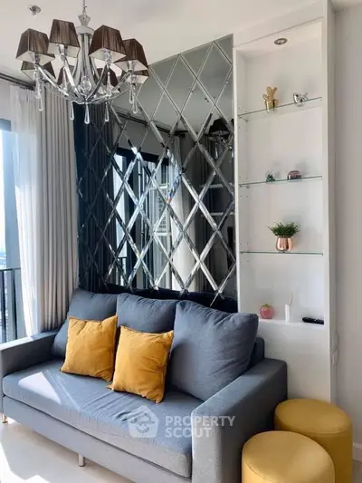 Stylish living room with modern chandelier, mirrored wall, and cozy sofa in bright apartment.