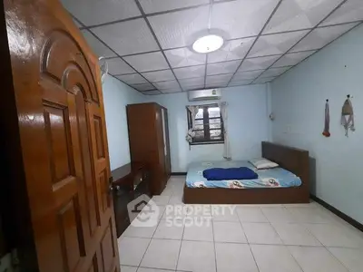 Spacious bedroom with tiled floor and wooden furniture, featuring a cozy bed and ample natural light.