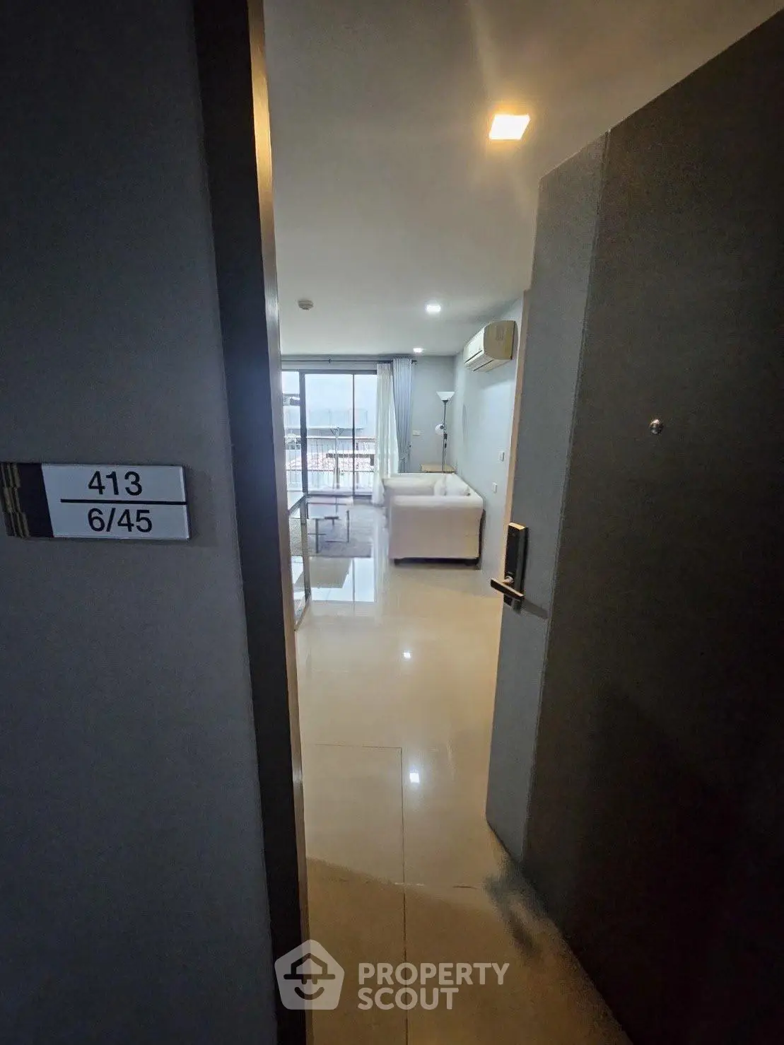 Modern apartment entrance leading to a cozy living room with a balcony view.