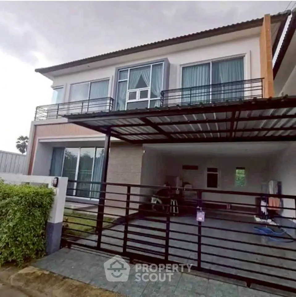 Modern two-story house with spacious carport and sleek balcony design.